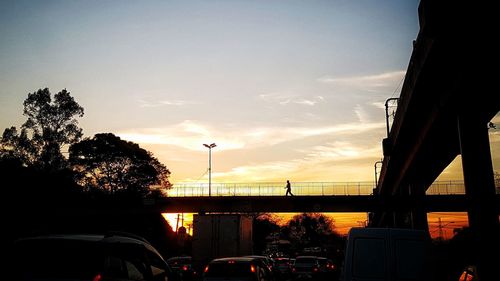 Silhouette bridge against sky during sunset in city