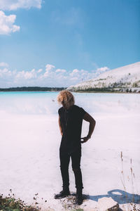 Rear view of man standing on beach against sky