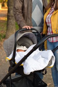 Young couple walking in park and pushing their baby in stroller