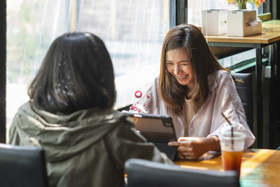 Young woman using mobile phone while sitting in cafe