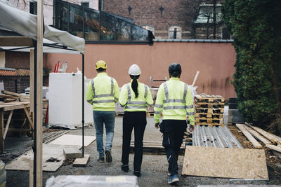 Rear view of male and female engineers walking at construction site