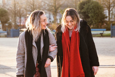 Smiling female friends talking while walking in park