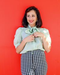 Portrait of beautiful young woman against red background