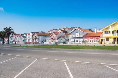 Road by houses against blue sky