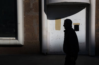 Side view of silhouette man walking against building