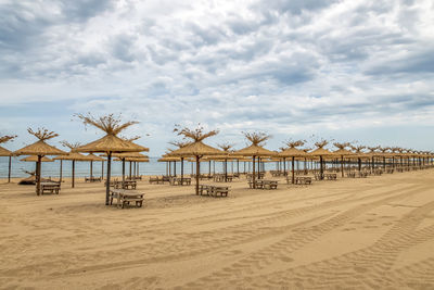 Deck chairs on beach against sky