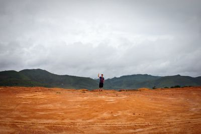 Scenic view of man waving against landscape