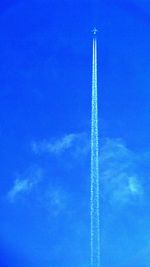 Low angle view of vapor trails in blue sky