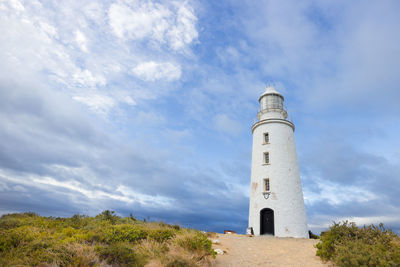 Low angle view of lighthouse amidst buildings against sky