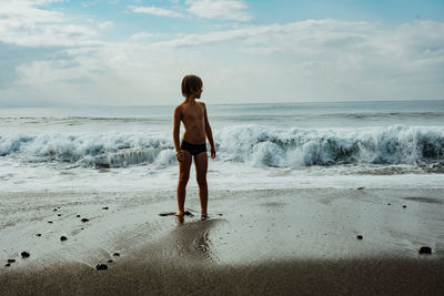 Rear view of shirtless man standing on beach