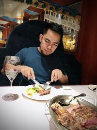 Young man sitting on table at restaurant