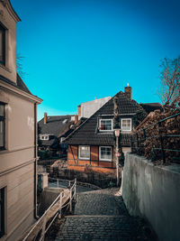 Footpath amidst buildings against blue sky