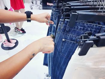 Cropped hands of woman choosing jeans in store