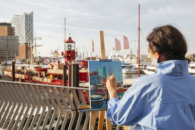 Artist painting at harbor on sunny day