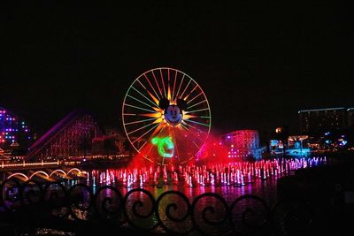 Illuminated ferris wheel against sky at night