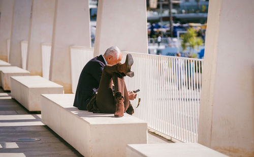 Elderly person resting on a bench near a marina, portraying contemplation or distress, surrounded 