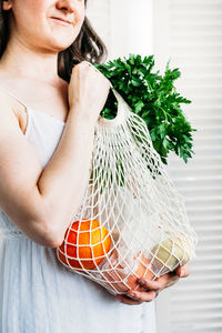 Midsection of woman carrying groceries in bag