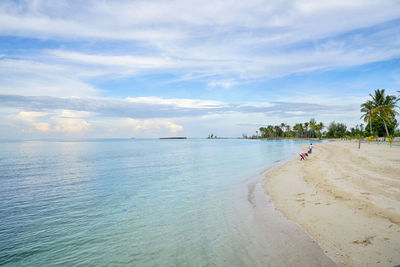 Scenic view of beach against cloudy sky