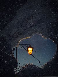 High angle view of puddle with reflection of illuminated street light at night