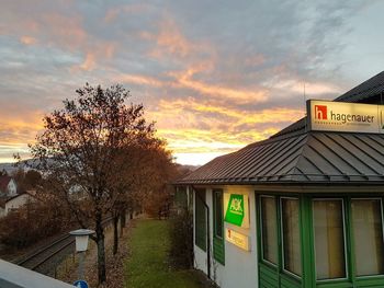 Information sign by house against sky during sunset