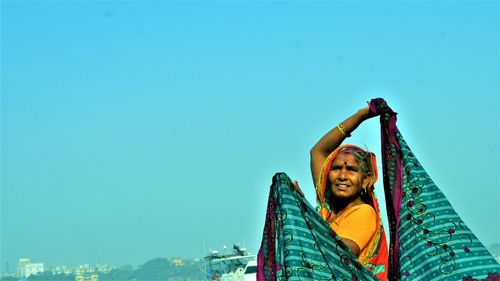 Low angle view of smiling woman against clear sky