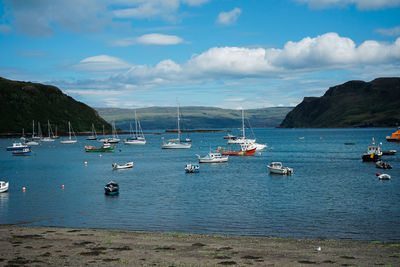 Sailboats moored in sea against sky