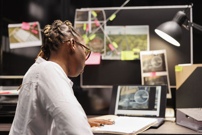 Side view of man using laptop while sitting on table