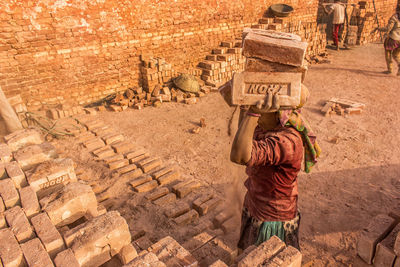 High angle view of woman carrying bricks on head