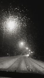 Close-up of wet illuminated street light at night