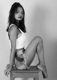 Portrait of woman sitting against wall