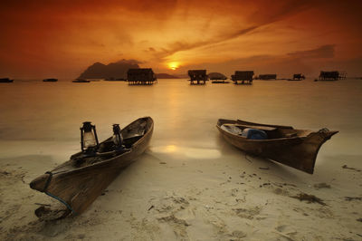 Boats moored on sea against sky during sunset