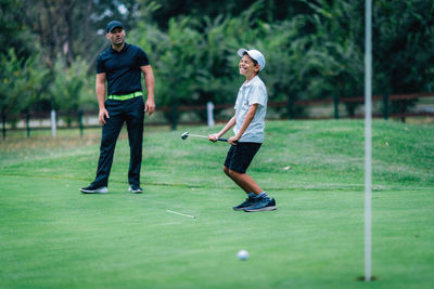 Full length of man playing with golf course