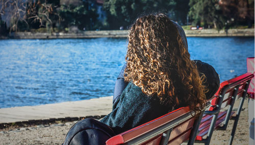 Woman sitting on bench at lakeshore