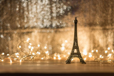 Close-up of small replica eiffel tower with illuminated string lights on table