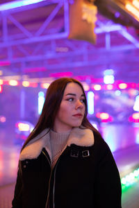 Portrait of beautiful woman standing at illuminated nightclub