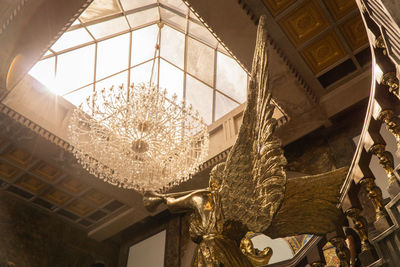 Low angle view of illuminated chandelier hanging on ceiling in building