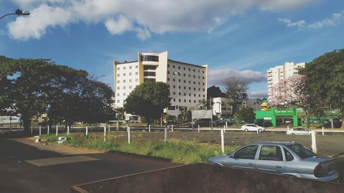 Road by buildings in city against sky