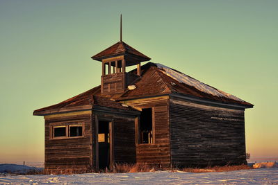 Exterior of house on field against clear sky during winter