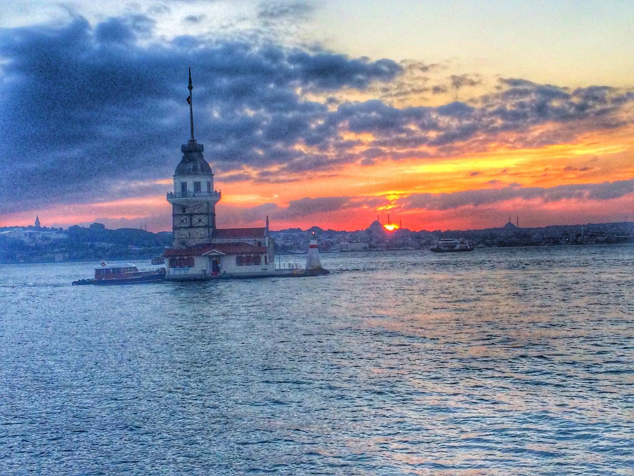 sunset, water, architecture, sky, built structure, building exterior, orange color, waterfront, sea, cloud - sky, scenics, nautical vessel, rippled, transportation, tower, silhouette, travel, travel destinations, beauty in nature, nature