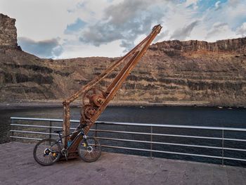 Bicycle on rock by mountain against sky