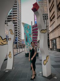 Portrait of woman standing on street against buildings in city