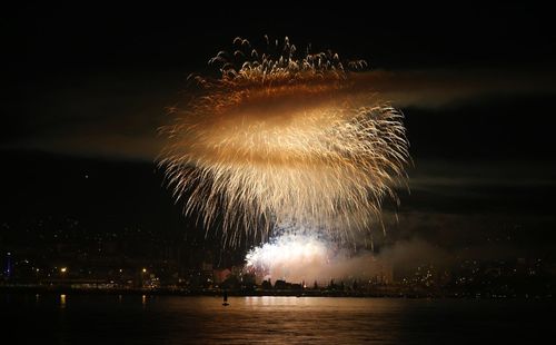 Low angle view of firework display over river at night