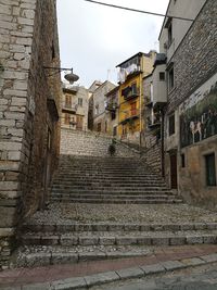 Low angle view of steps amidst buildings against sky