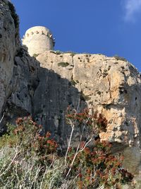 Low angle view of rocks against clear blue sky