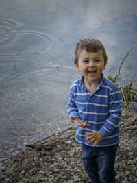 Happy smiling little boy after throwing pebbles into a pond