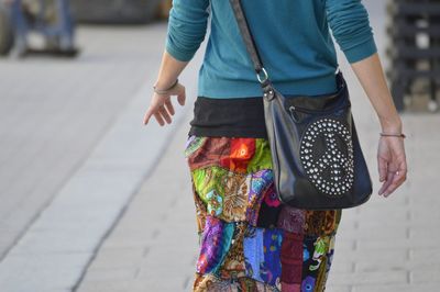 Midsection of woman with purse walking on footpath