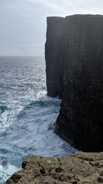 Rock formation on beach against sky