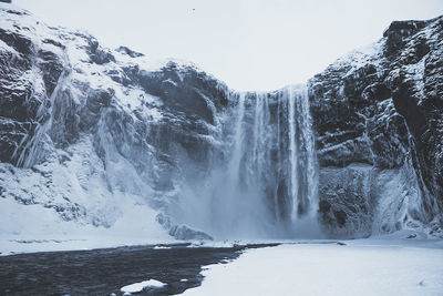 Scenic view of waterfall against clear sky during winter