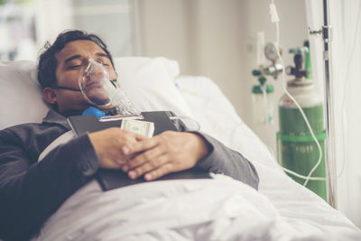 Patient with paper currency and clipboard lying on hospital bed