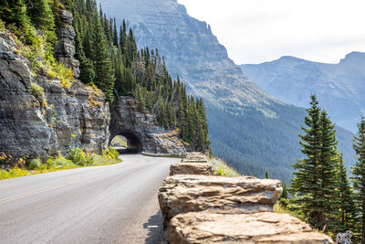 Road amidst trees and mountains against sky